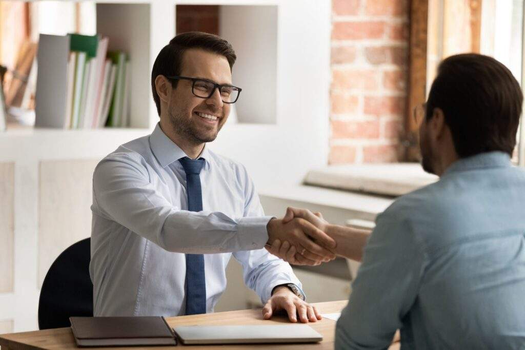 Man-smiling-giving-firm-handshake-at-job-interview